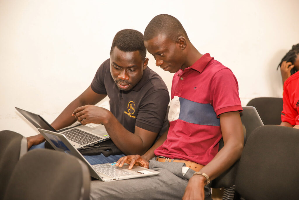 Two men sitting on a couch looking at laptop