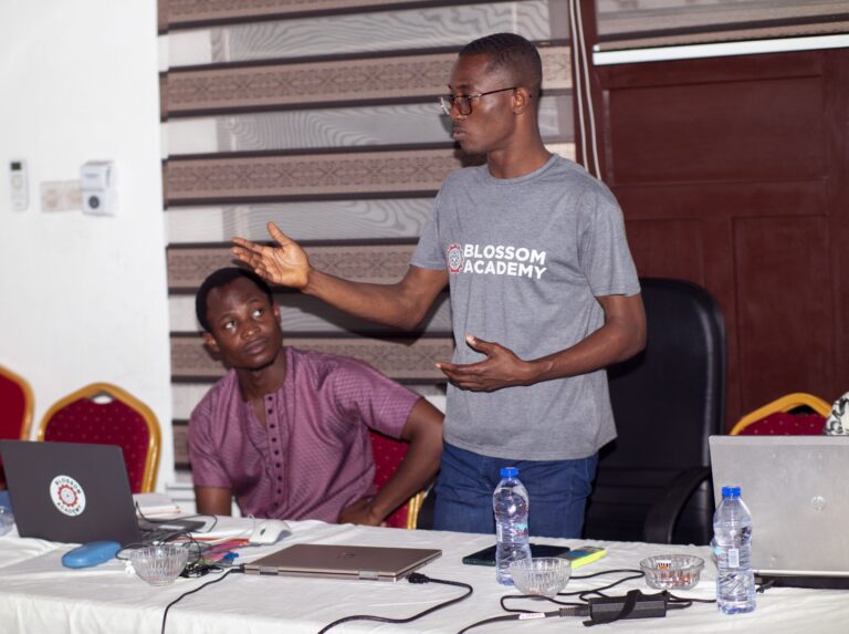 A man standing at the table with another man.