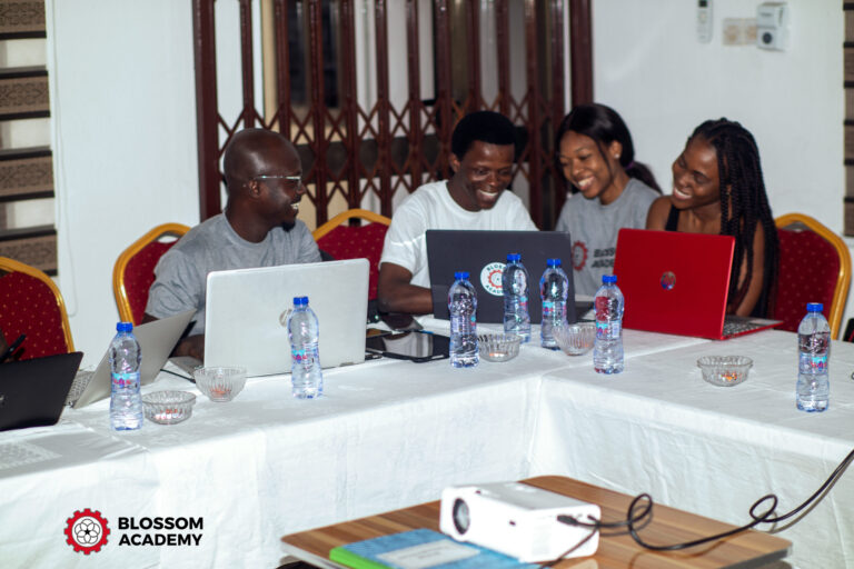 A group of people sitting around a table with laptops.