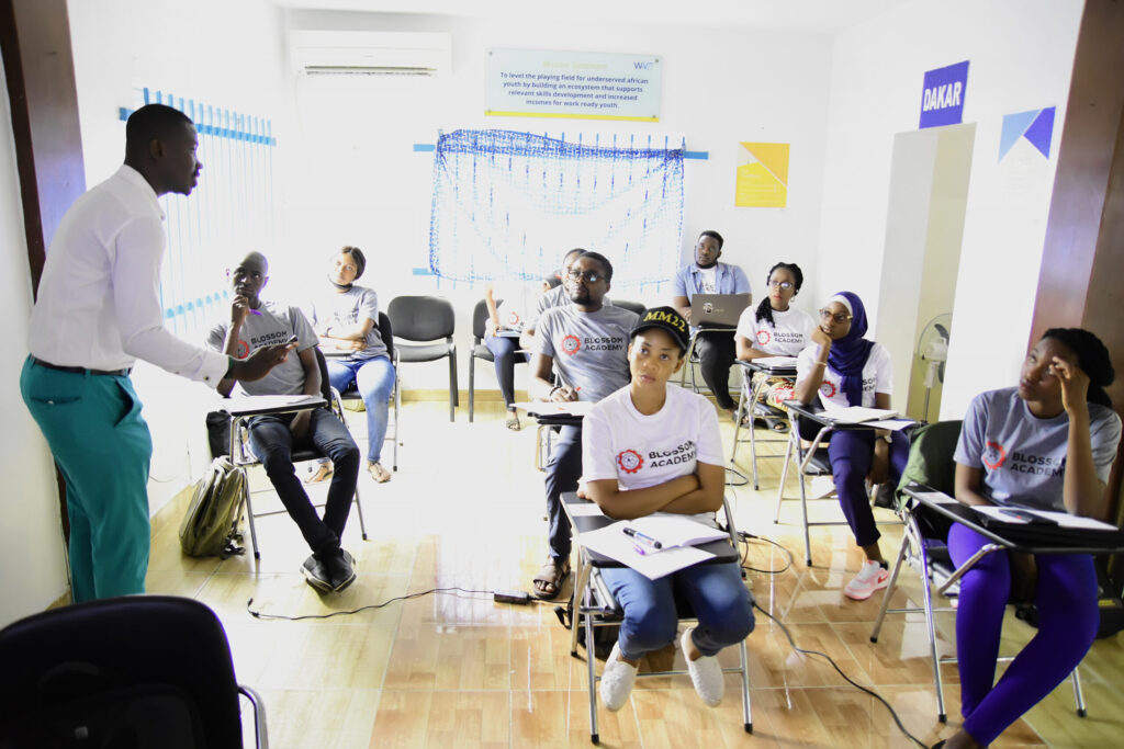 A group of people sitting in chairs and one person standing up.