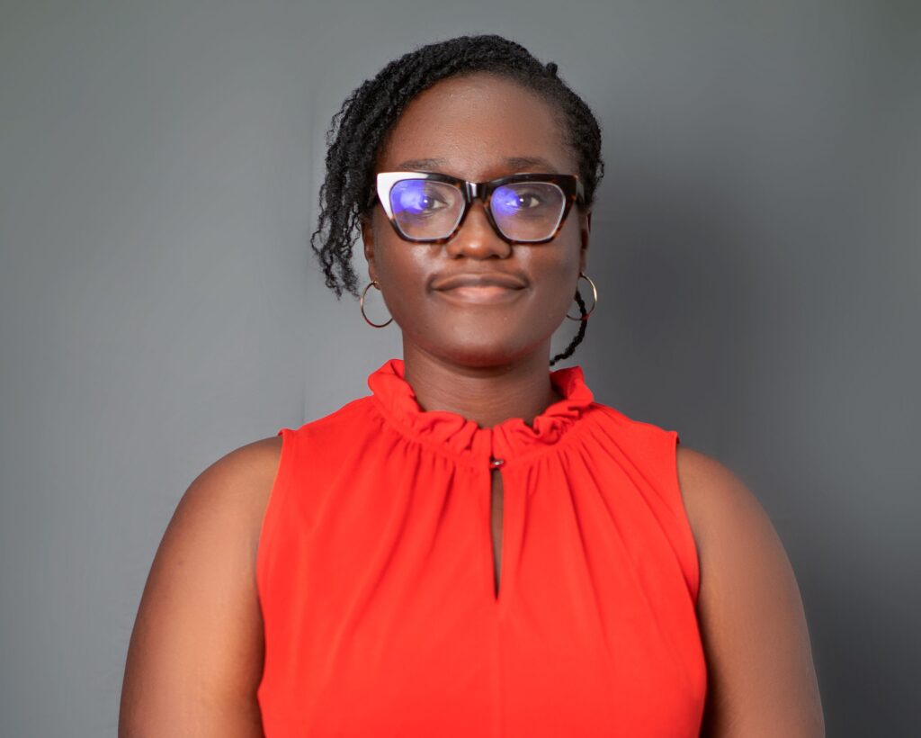 A woman in red shirt wearing glasses and smiling.