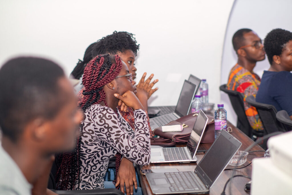 A group of people sitting at tables with laptops.