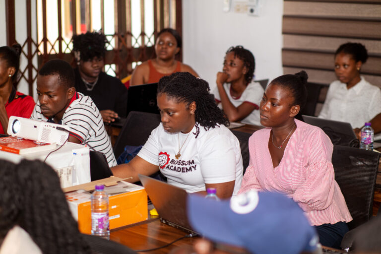 A group of people sitting around a table with laptops.